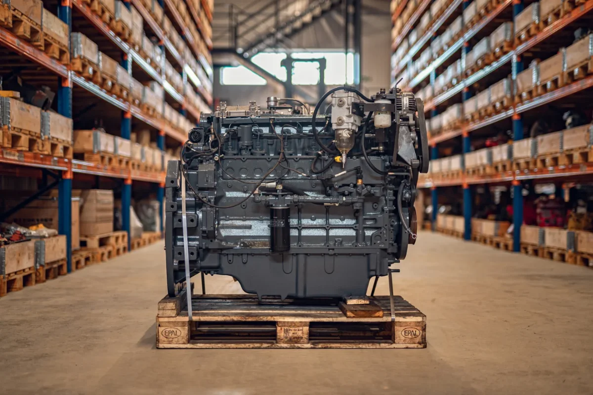 Rebuilt six-cylinder diesel engine on a pallet in a parts warehouse with shelving