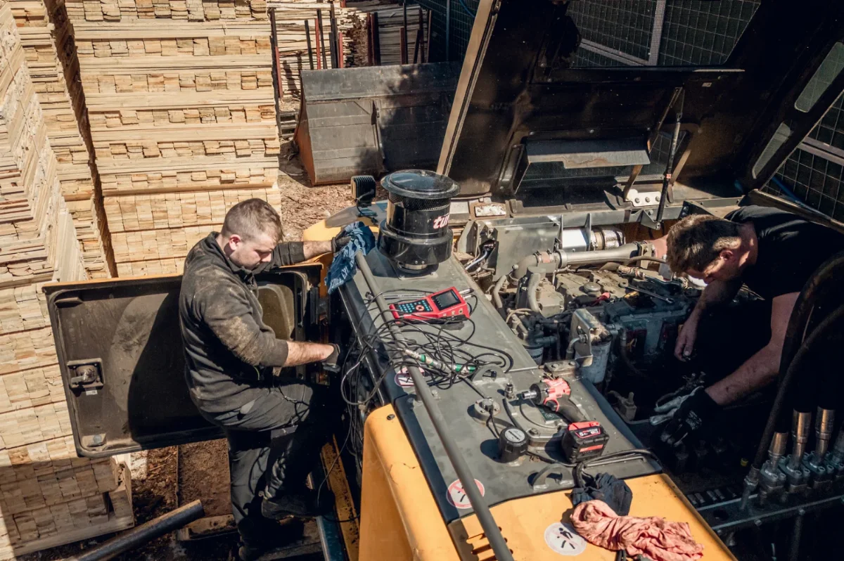 Mechanics diagnosing and repairing a construction machine engine in the field