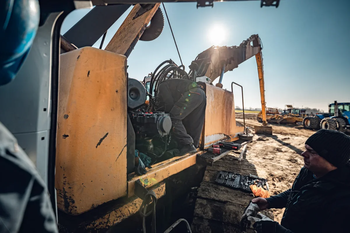 Mechanic working on an excavator hydraulic pump during an on-site repair