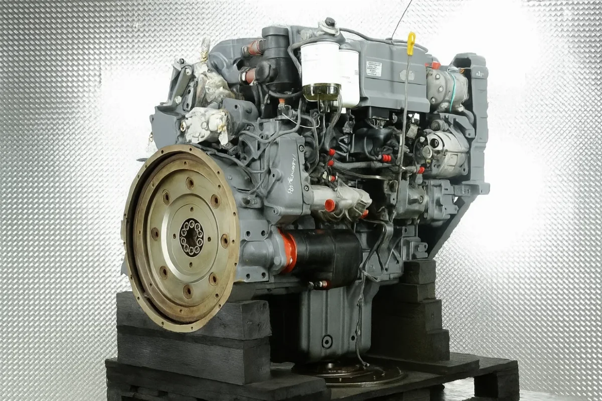 Four-cylinder Liebherr engine on a pallet, flywheel side view with fuel filters and ancillaries