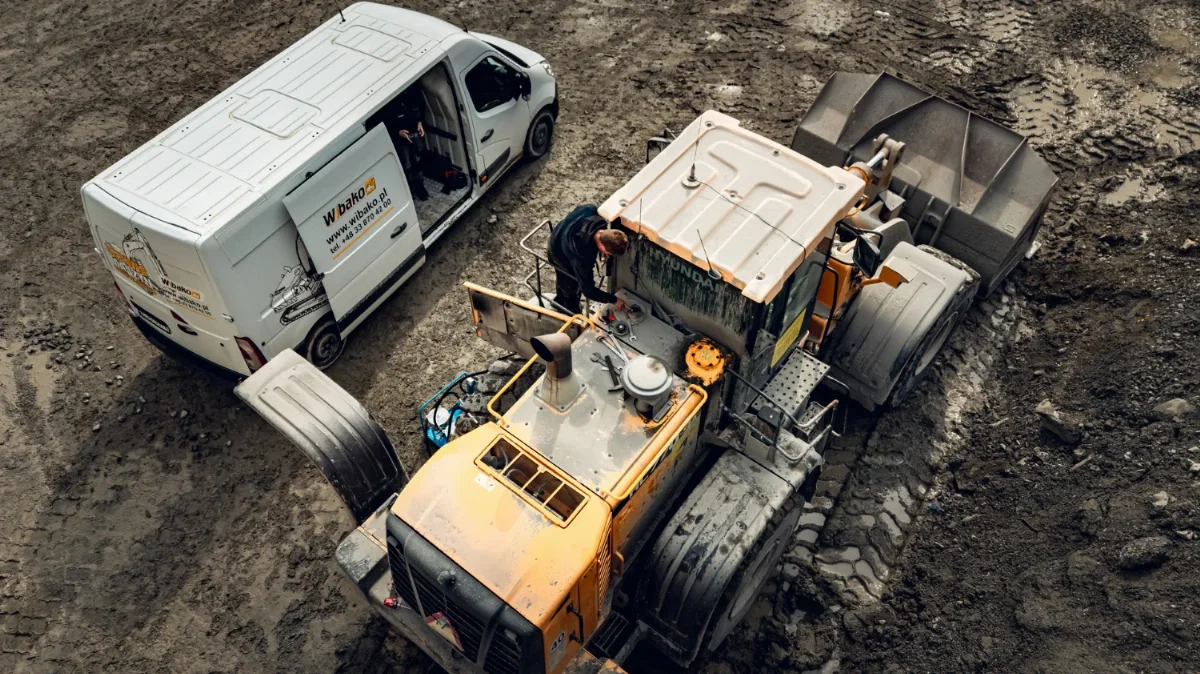 WIBAKO mechanic servicing a wheel loader in the field, service van with open doors nearby