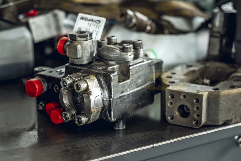 Remanufactured hydraulic pump with capped ports and a Wibako tag on a workshop bench
