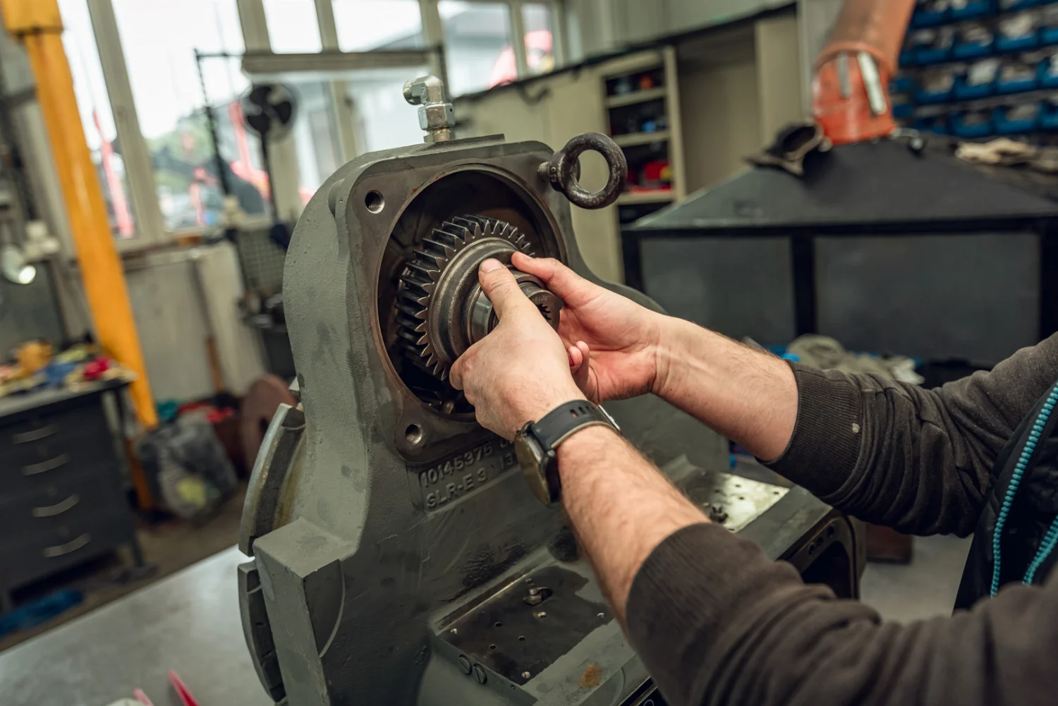 Mechanic fitting a gear wheel into a gearbox housing during an overhaul in the workshop