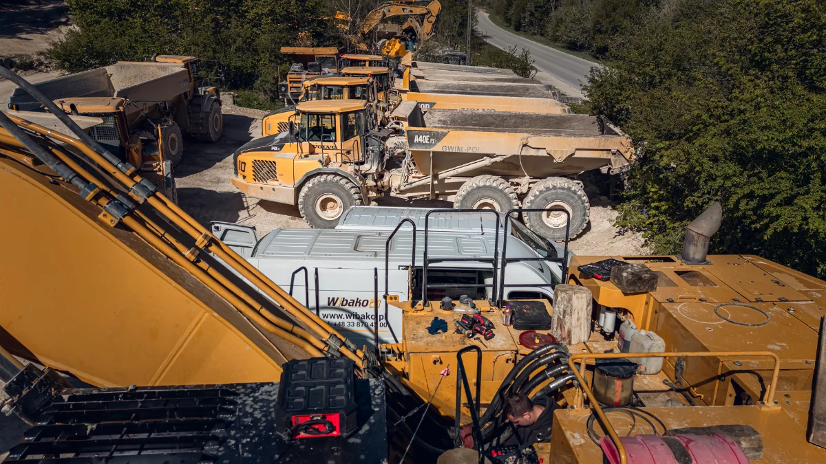 On-site excavator service at a quarry, articulated dump trucks and a Wibako service van in the background