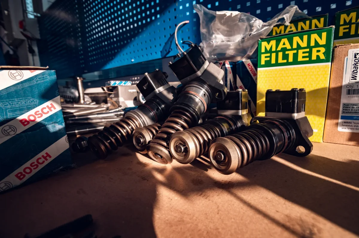 Diesel engine unit injectors on a workbench next to Bosch parts packaging and Mann Filter filters