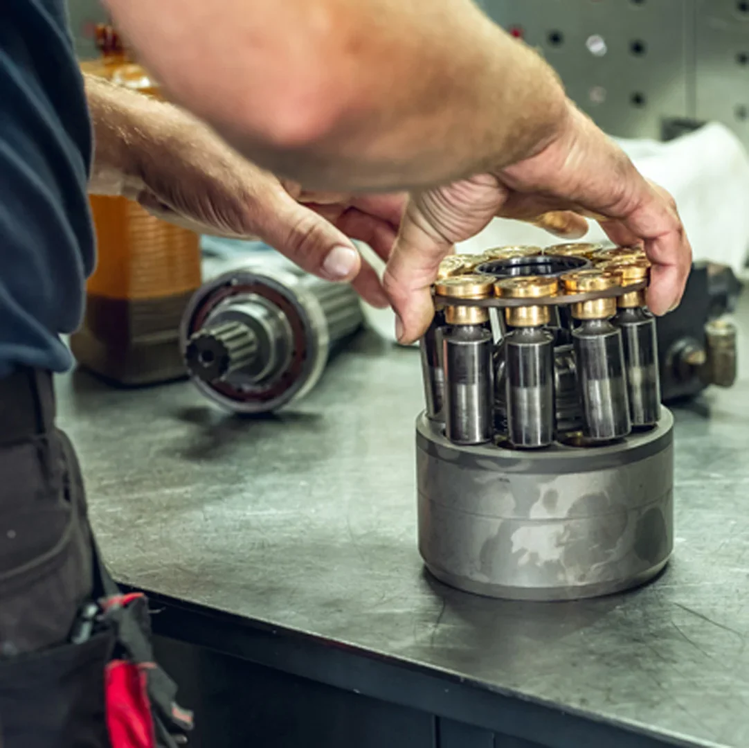 Mechanic assembling a cylinder block with pistons on a workbench, shaft with bearing alongside