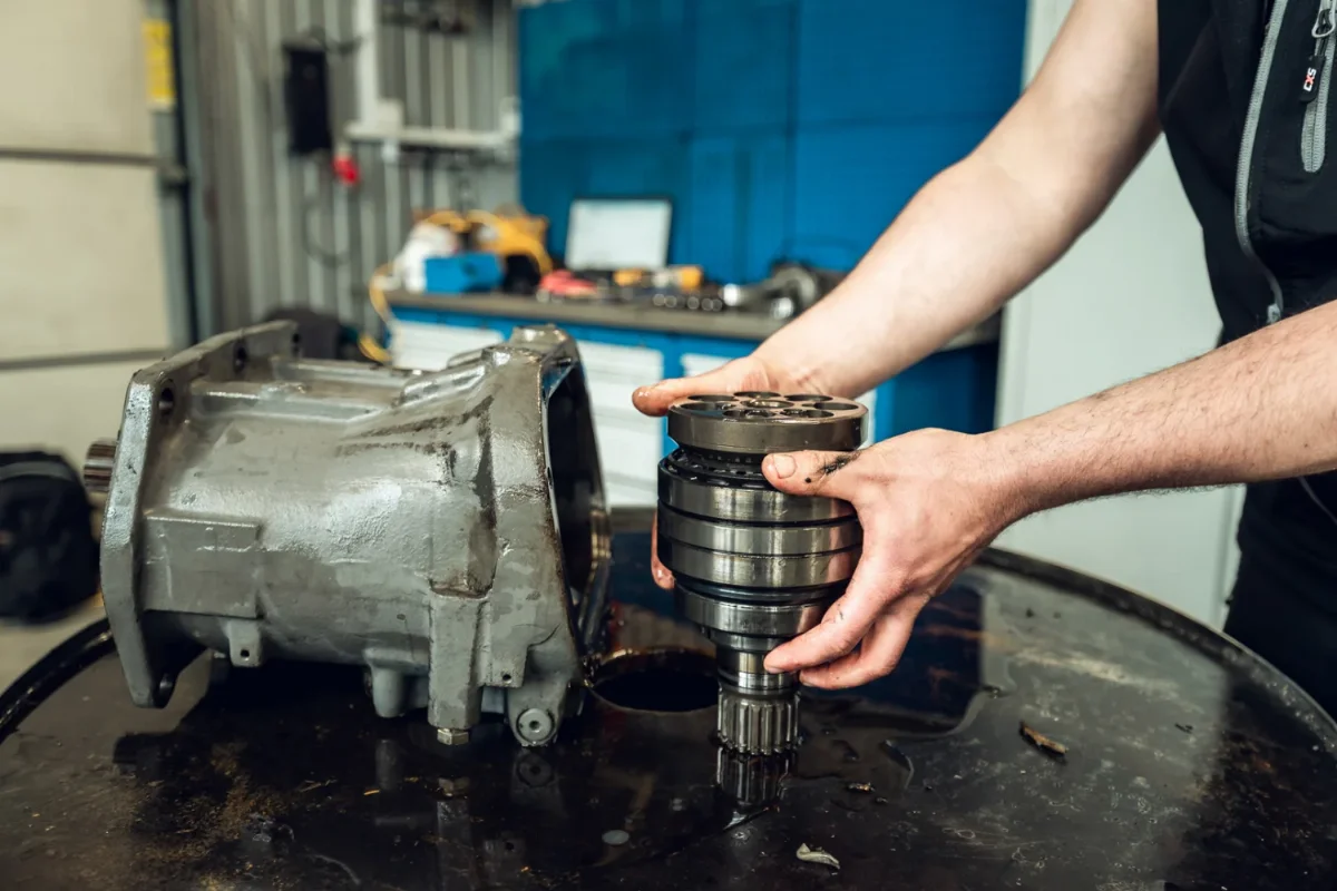 Mechanic holding a rotating group with splined shaft next to the housing of a hydraulic piston unit