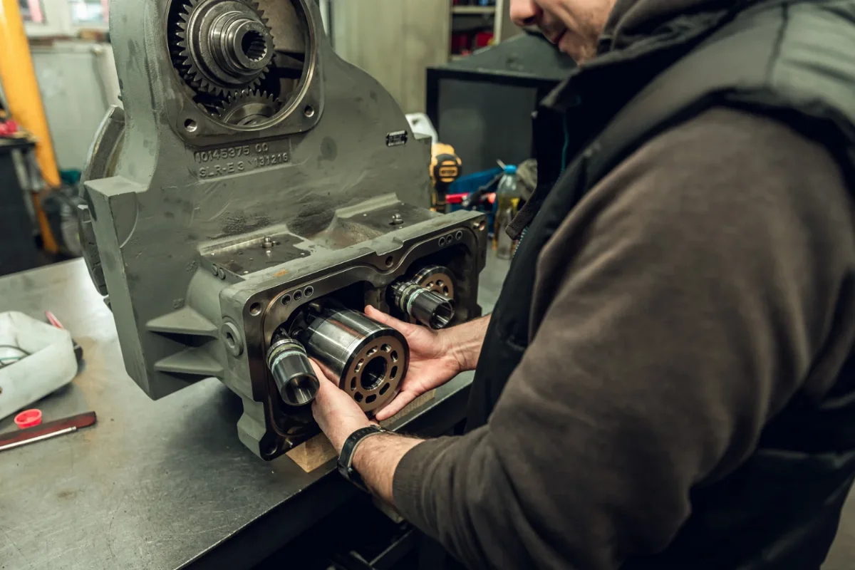 Mechanic inserting the cylinder block into a hydraulic pump housing during reassembly after rebuild
