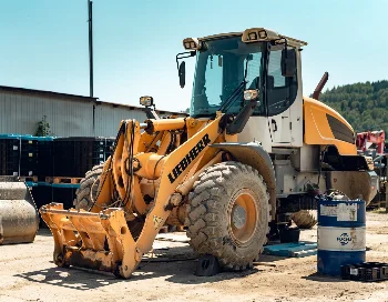 Liebherr wheel loader chocked on a service yard, with a Fuchs oil drum next to it