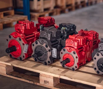Red and grey hydraulic piston pumps with labels on a wooden pallet in a warehouse
