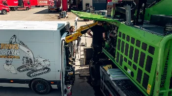 Mechanics servicing the engine of a Sennebogen material handler next to a service van with a HIAB crane