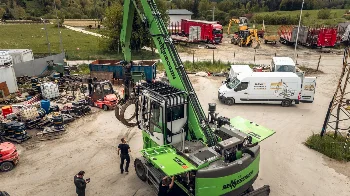 Servicing a Sennebogen 730 E material handler with grapple, WIBAKO service van parked on the yard