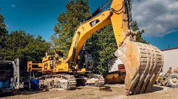 Large CAT crawler excavator with rock bucket during on-site service, mobile service van nearby
