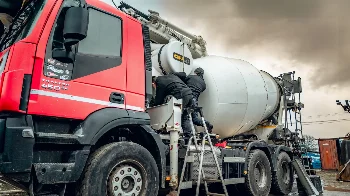 Mechanics working on a CIFA concrete mixer on an Iveco Trakker 450 chassis at a service yard