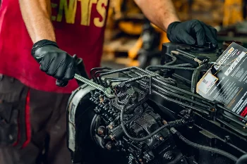 Mechanic in gloves tightening diesel engine injection lines with a wrench, WIBAKO tag attached