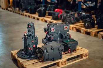 Remanufactured hydraulic pumps and a hydraulic motor on a pallet in a warehouse with more components behind