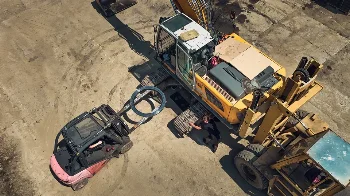 Aerial view of a crawler excavator and forklift carrying a slewing ring during on-site repair in a yard