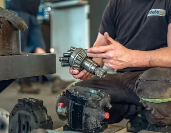 WIBAKO mechanic holding a hydraulic pump piston assembly next to the dismantled pump housing