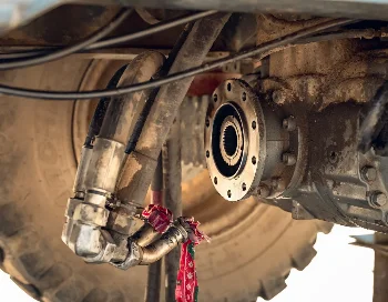 Dirty transmission of a construction machine with splined output flange and hydraulic hoses near the wheel