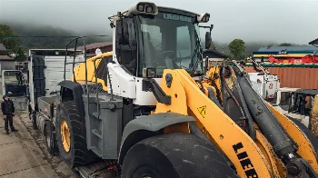 Liebherr wheel loader loaded on a truck trailer for transport to the service yard on a foggy day
