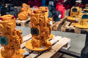 Yellow remanufactured hydraulic pumps with capped ports and labels, ready for shipment on pallets