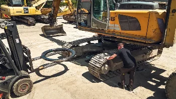 Mounting a slewing ring on a Liebherr excavator undercarriage using a Linde forklift at a service yard