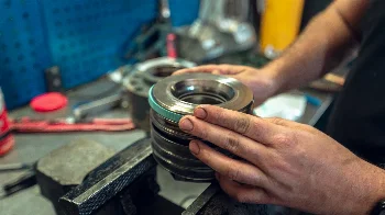 Mechanic's hands assembling a stack of discs and rings with a seal on a workshop vise